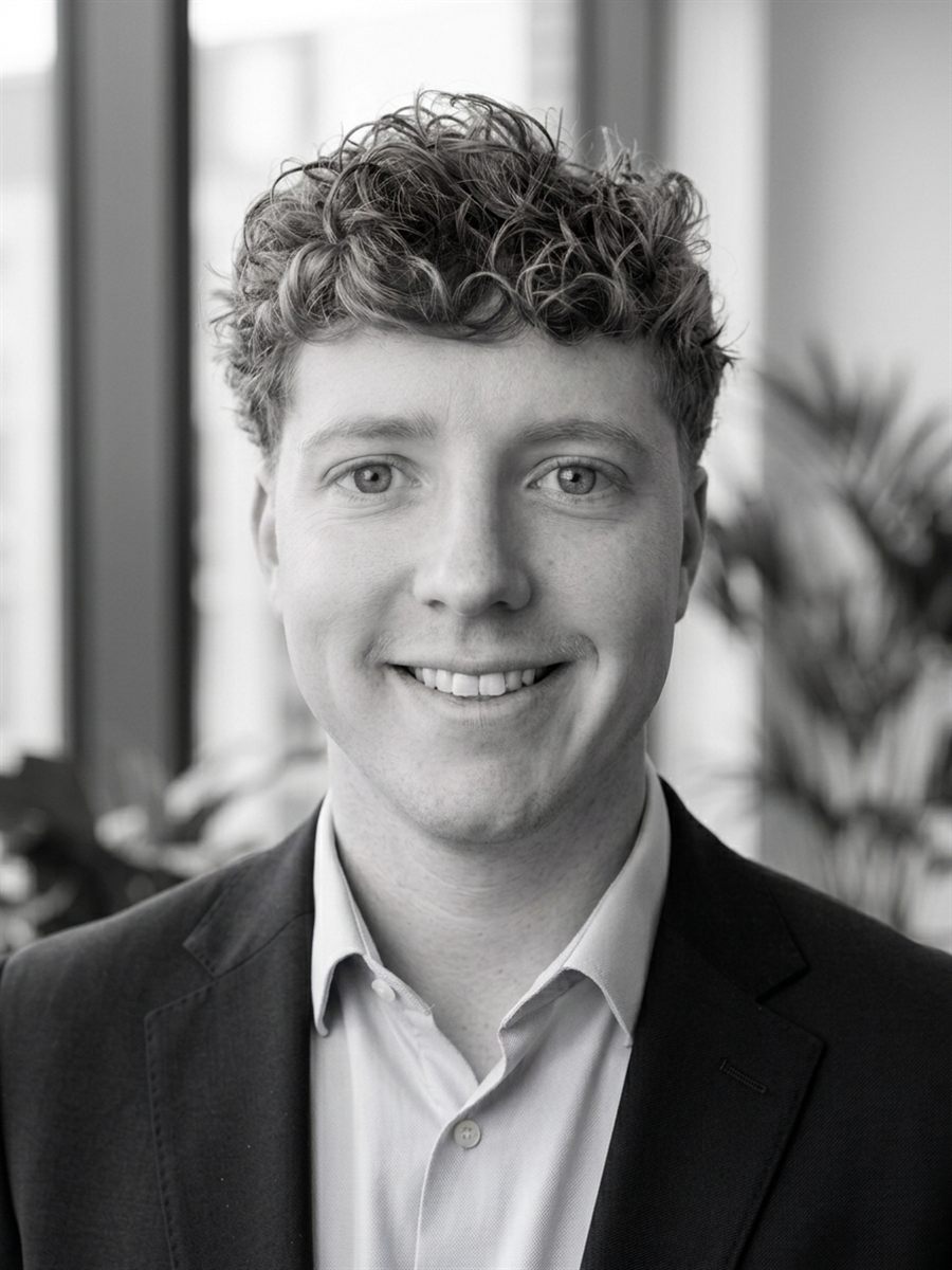 Black and white portrait of Simeon Venter smiling, wearing a blazer and open-collar shirt